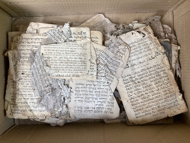 Karton mit im Zerfall befindlichen Blättern in hebräischer Schrift
