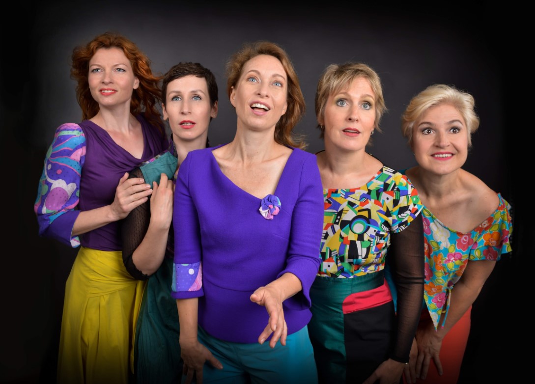 Fünf Frauen singen vor dunklem Hintergrund