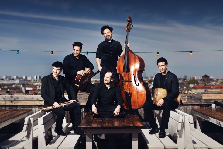 Fünf Musiker mit Instrumenten vor Stadtsilouhette