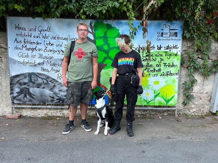 Mann und Frau mit Hund vor einem Plakat
