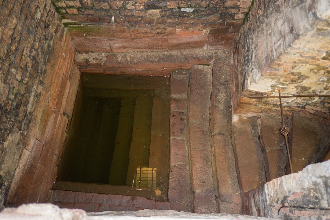 Gemauerter Schacht mit einer hinabführenden Treppe zu stehendem Wasser 